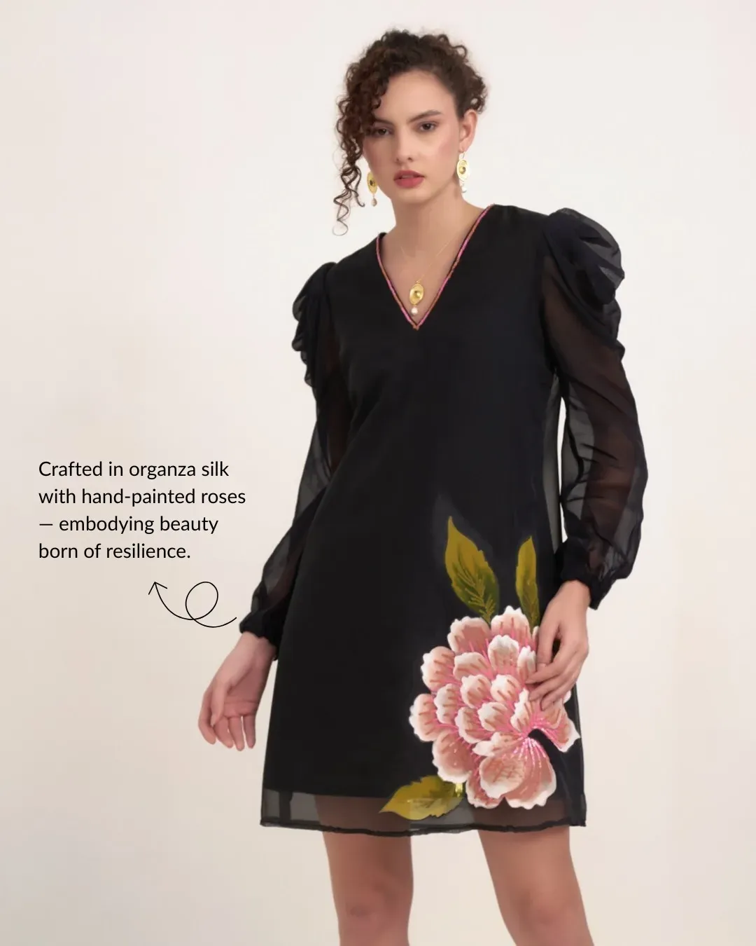 Model in a black organza dress with hand-painted pink roses on a pale backdrop